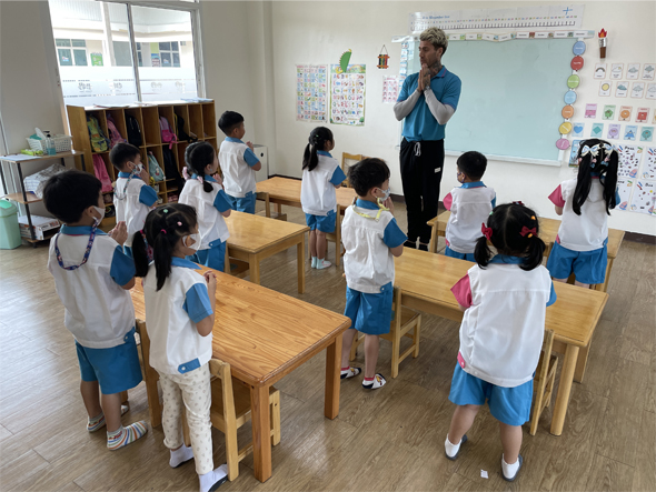 Students are greeting their teacher in a TEFL classroom in Thailand.